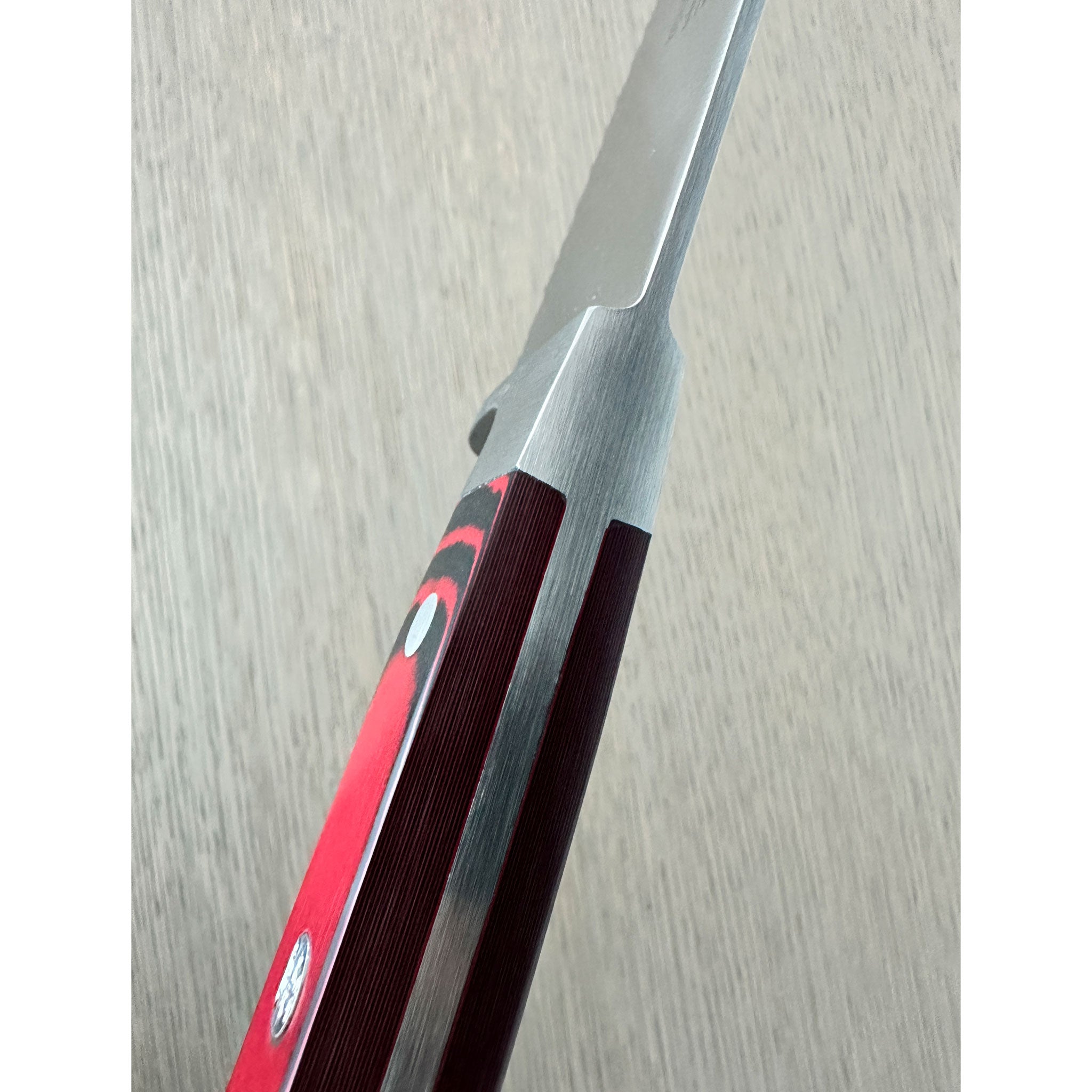 A Güde Micarta serrated bread knife spine close up.