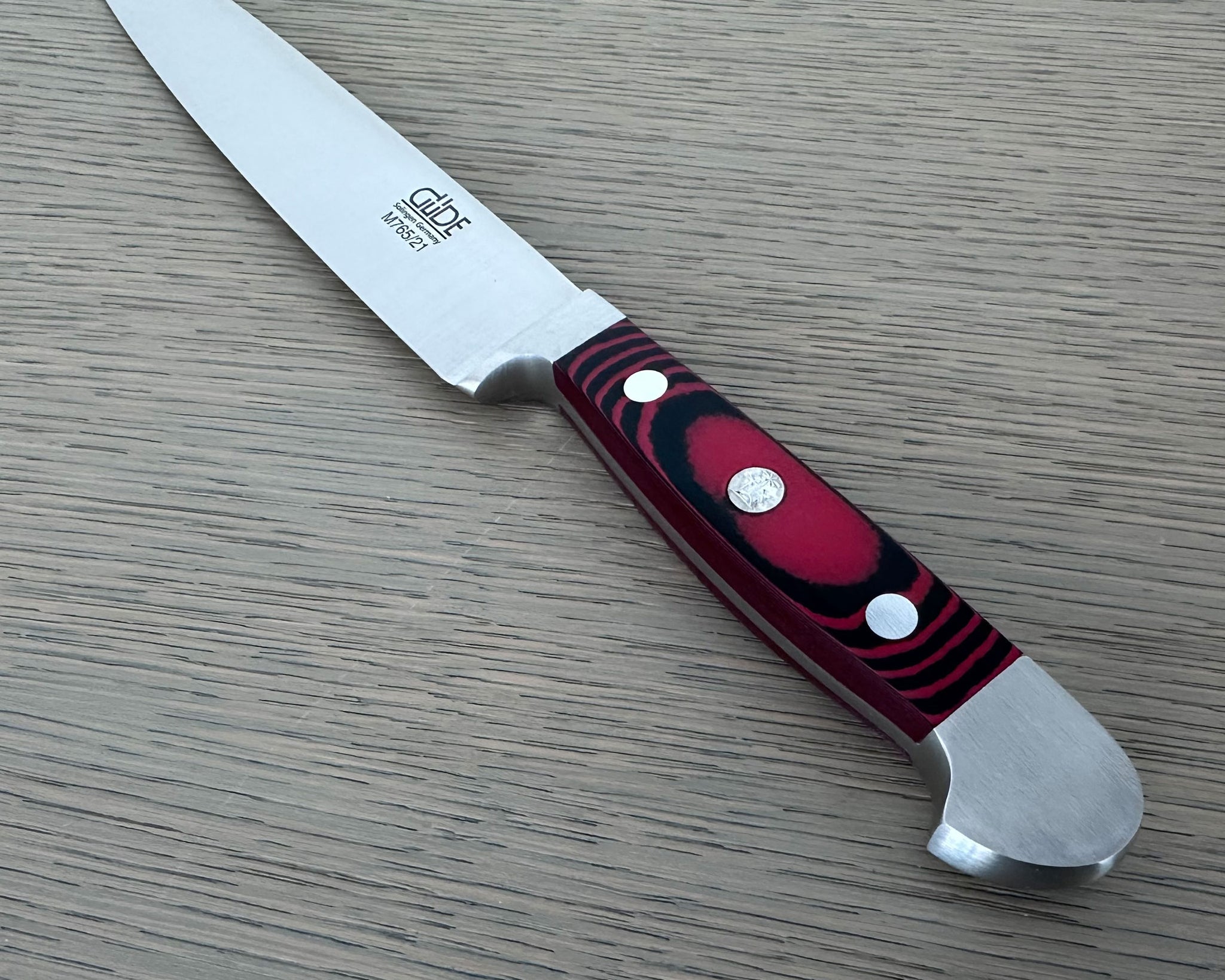 A Gude Micarta Slicing knife displayed diagonally on a light gray wood-grain surface.