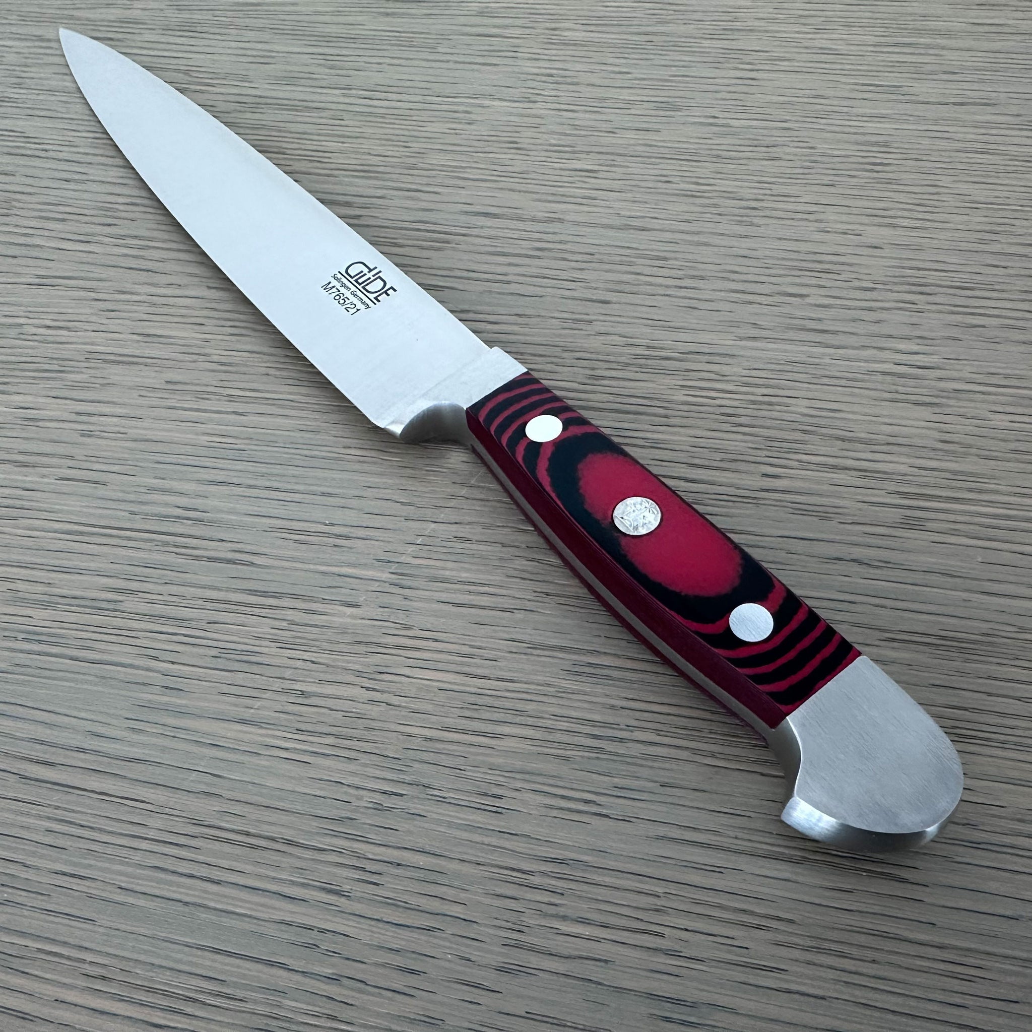 A Gude Micarta Slicing knife displayed diagonally on a light gray wood-grain surface.